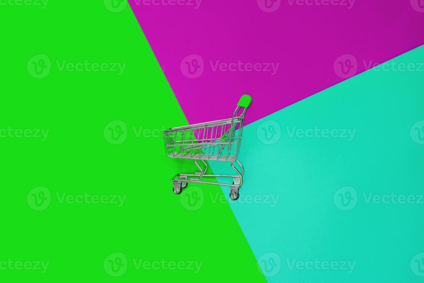 Top view of empty shopping trolley on colorful bright background. Concept of shopping and consumerism. Minimal flat lay. photo