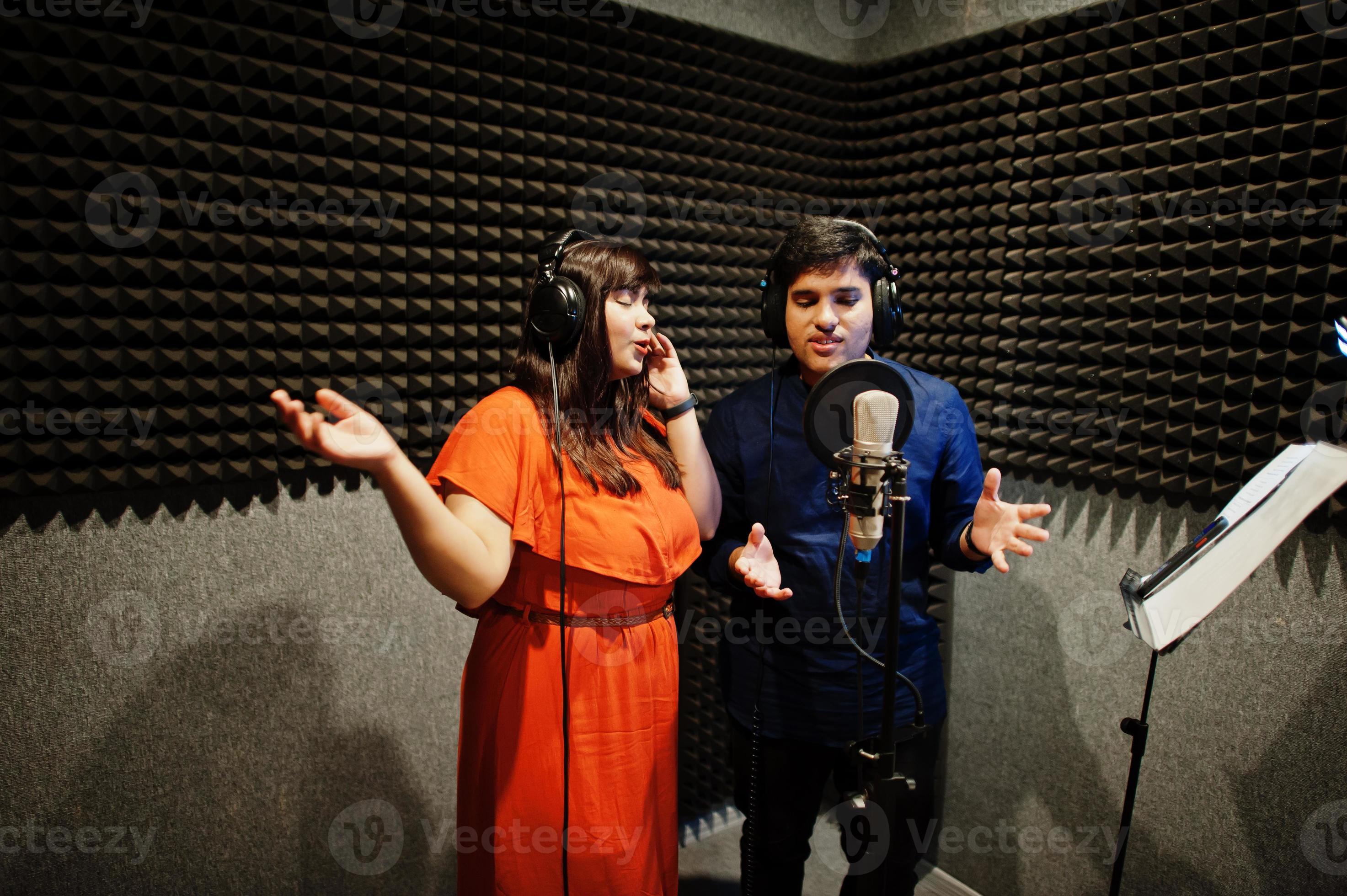 Young asian duet singers with microphone recording song in record music