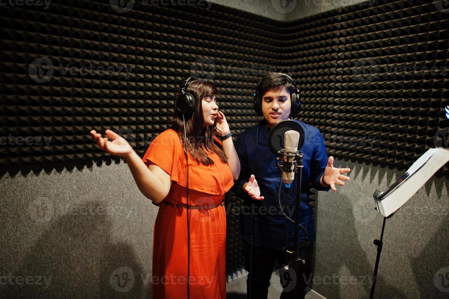 Young asian duet singers with microphone recording song in record music studio. photo
