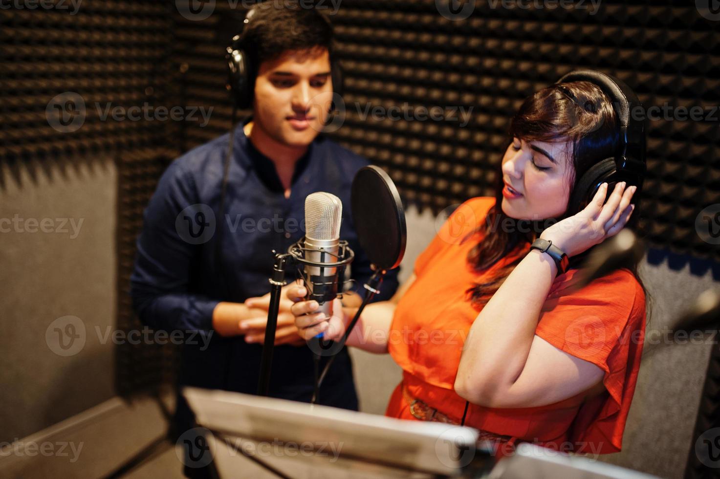 Young asian duet singers with microphone recording song in record music studio. photo