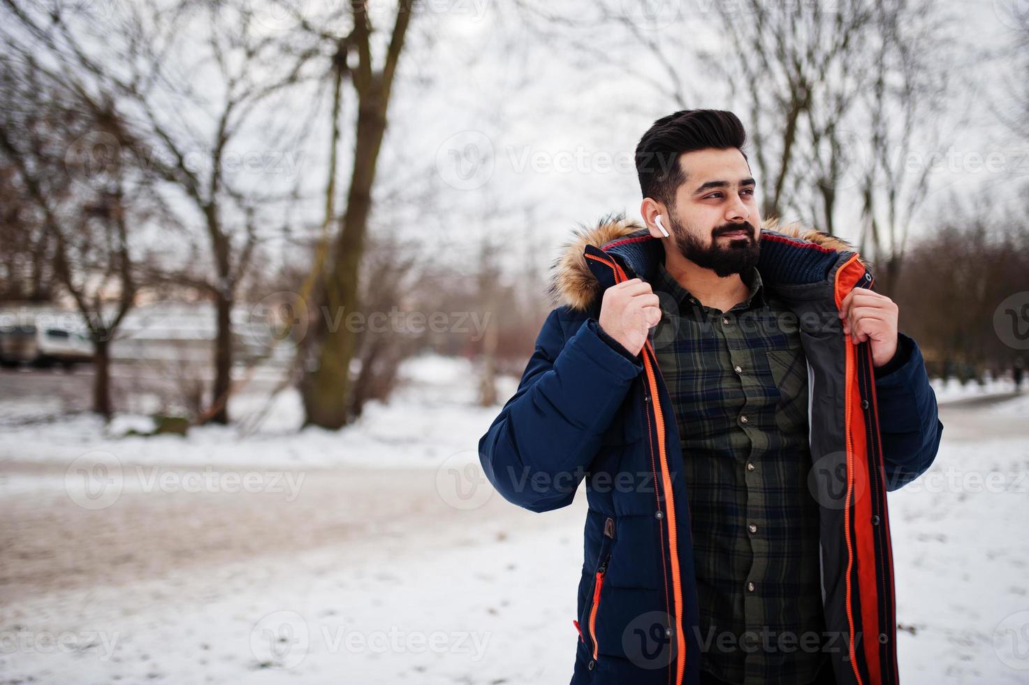 Beard indian man wear jacket in cold winter day. Mobile earphones in ears. photo