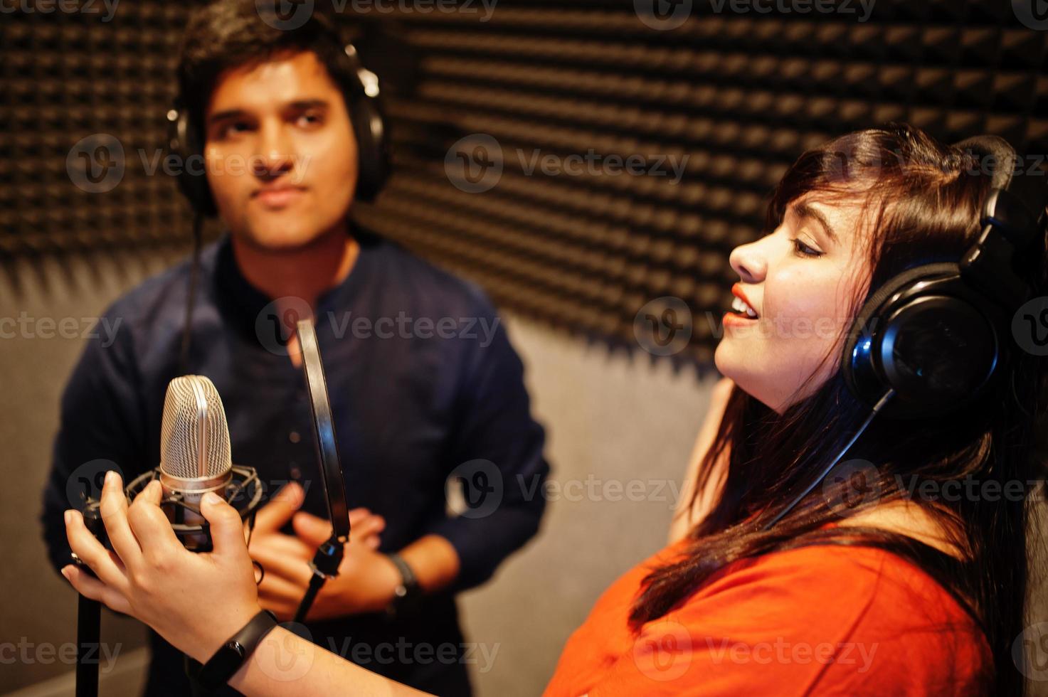 Young asian duet singers with microphone recording song in record music studio. photo