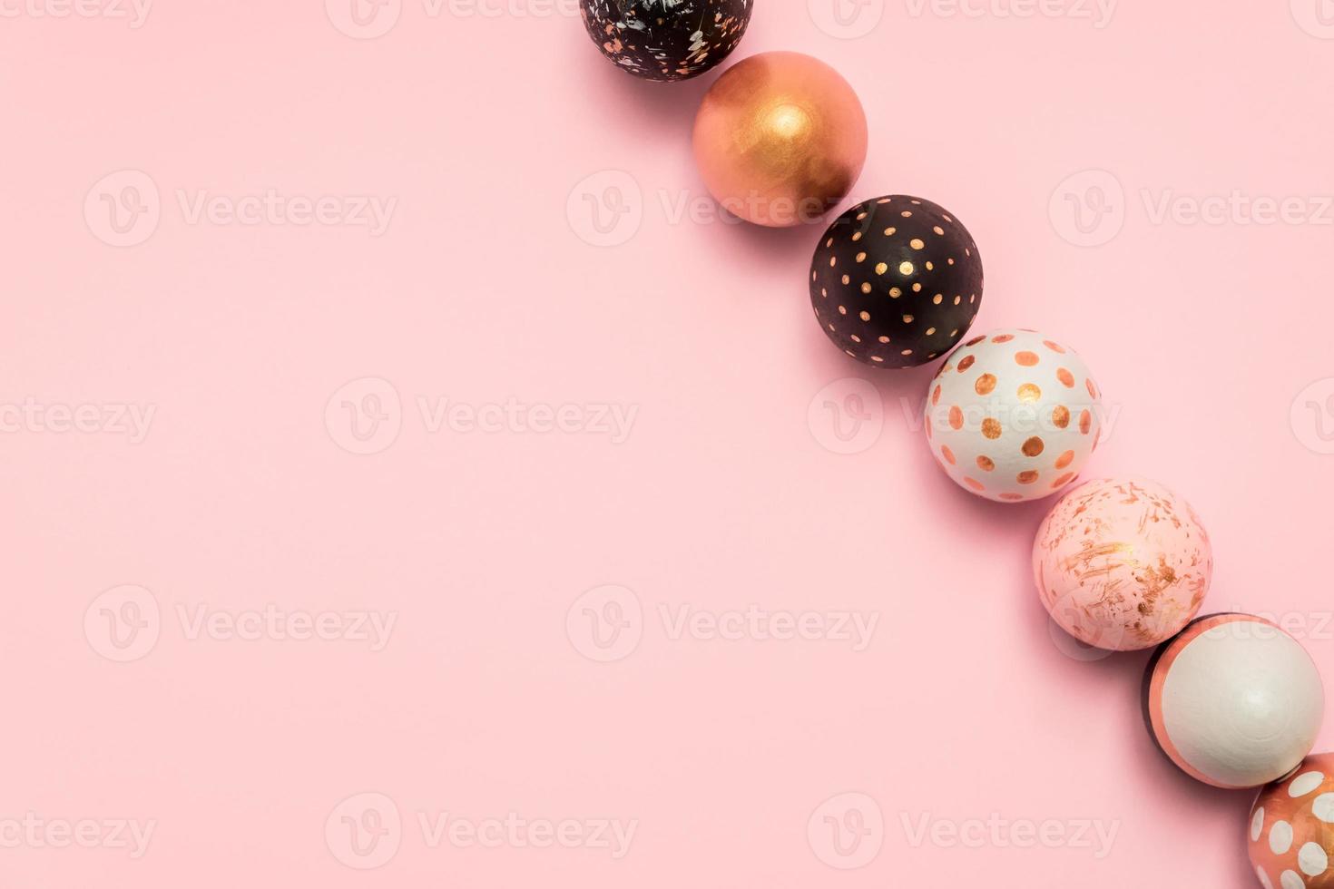 Pink background with colorful easter eggs in a row painted in gold, white and black colors. Creative layout with copy space photo