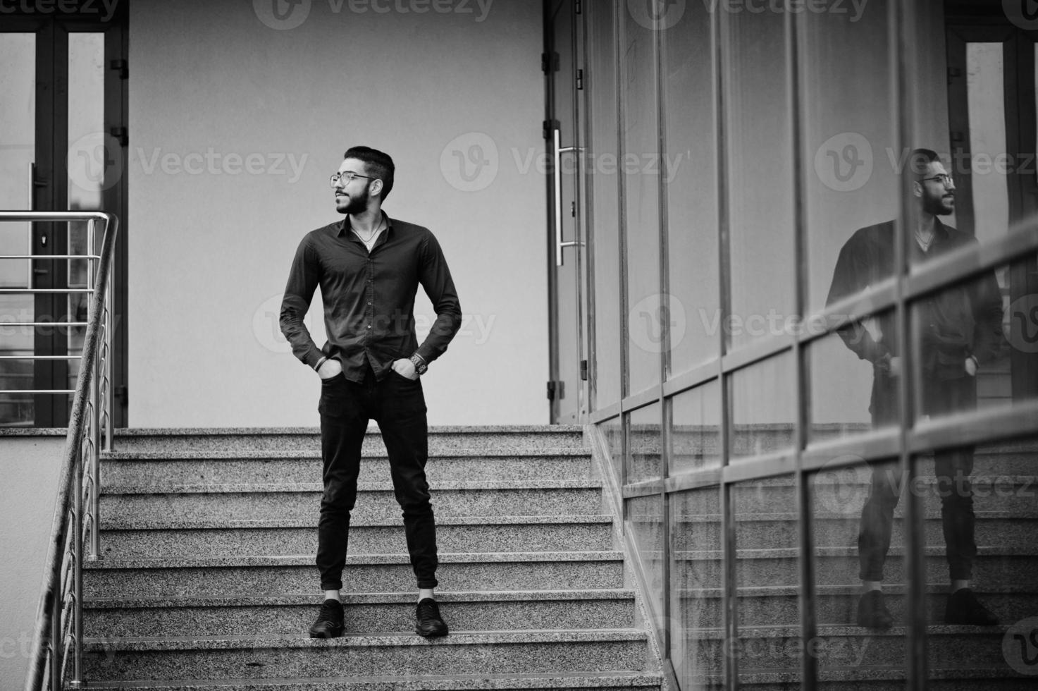 Middle eastern entrepreneur wear blue shirt, eyeglasses against office building. photo