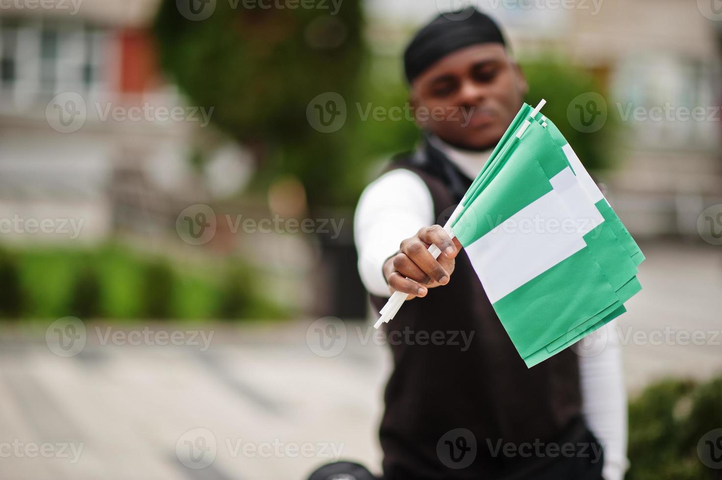 Young african american man hold nigerian flags in hands. photo