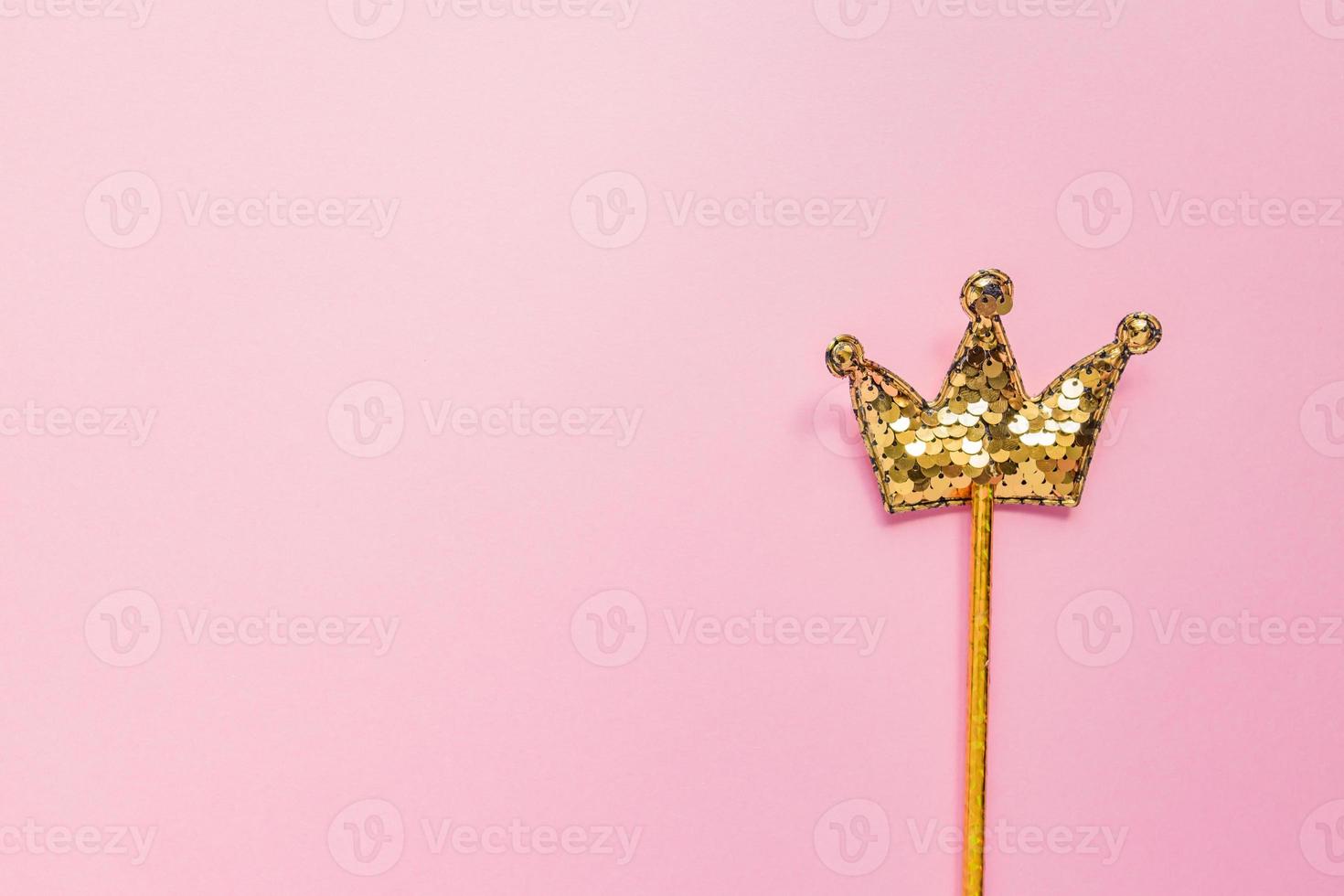 golden magic stick from sequins in crown shape on pastel pink backgeound. Creative flat lay in minimal style. Copy space for text photo