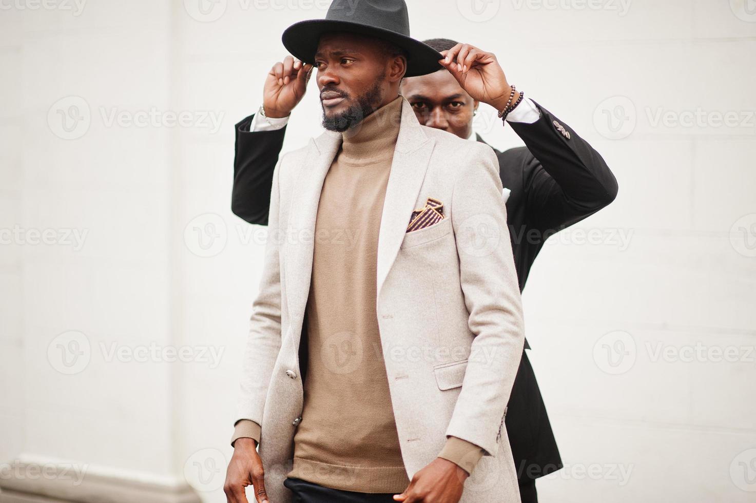 dos hombres negros de moda. retrato de moda de modelos masculinos afroamericanos. llevar traje, abrigo y sombrero. foto