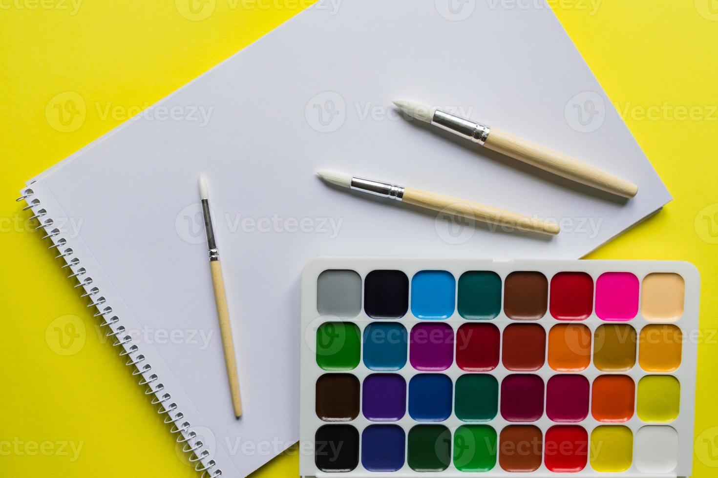 Creative layout with aquarelle palette, paint brushes and sketchbook on