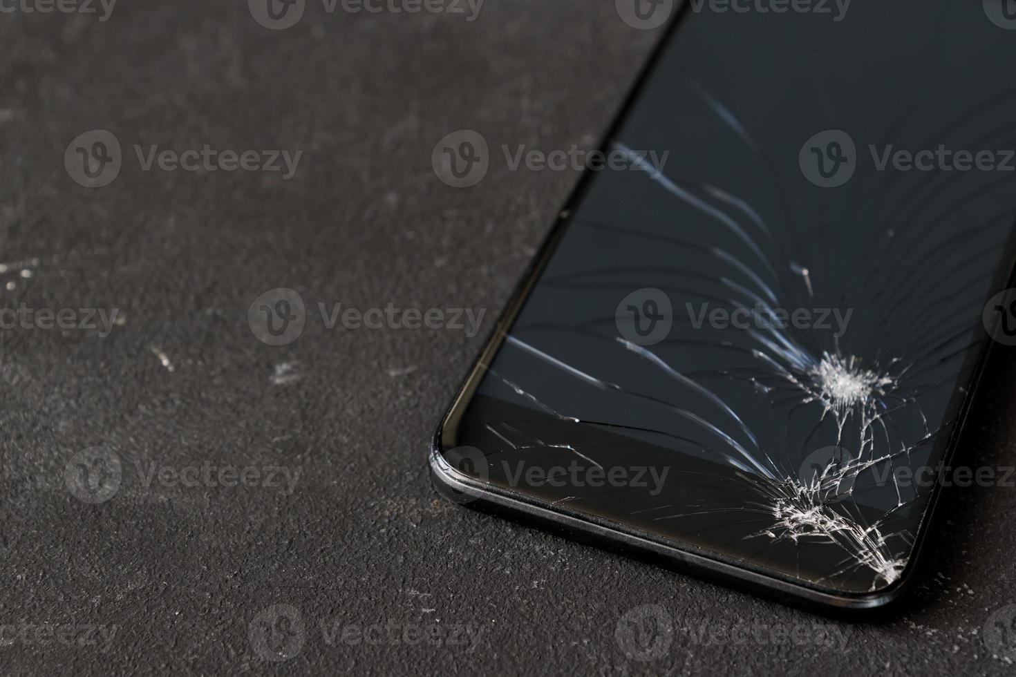 Broken glass of black smart phone on the dark background. Selective focus. Copy space photo