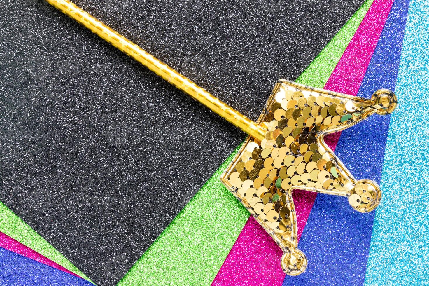 golden magic stick from sequins in crown shape on glitter background. Creative flat lay close up photo