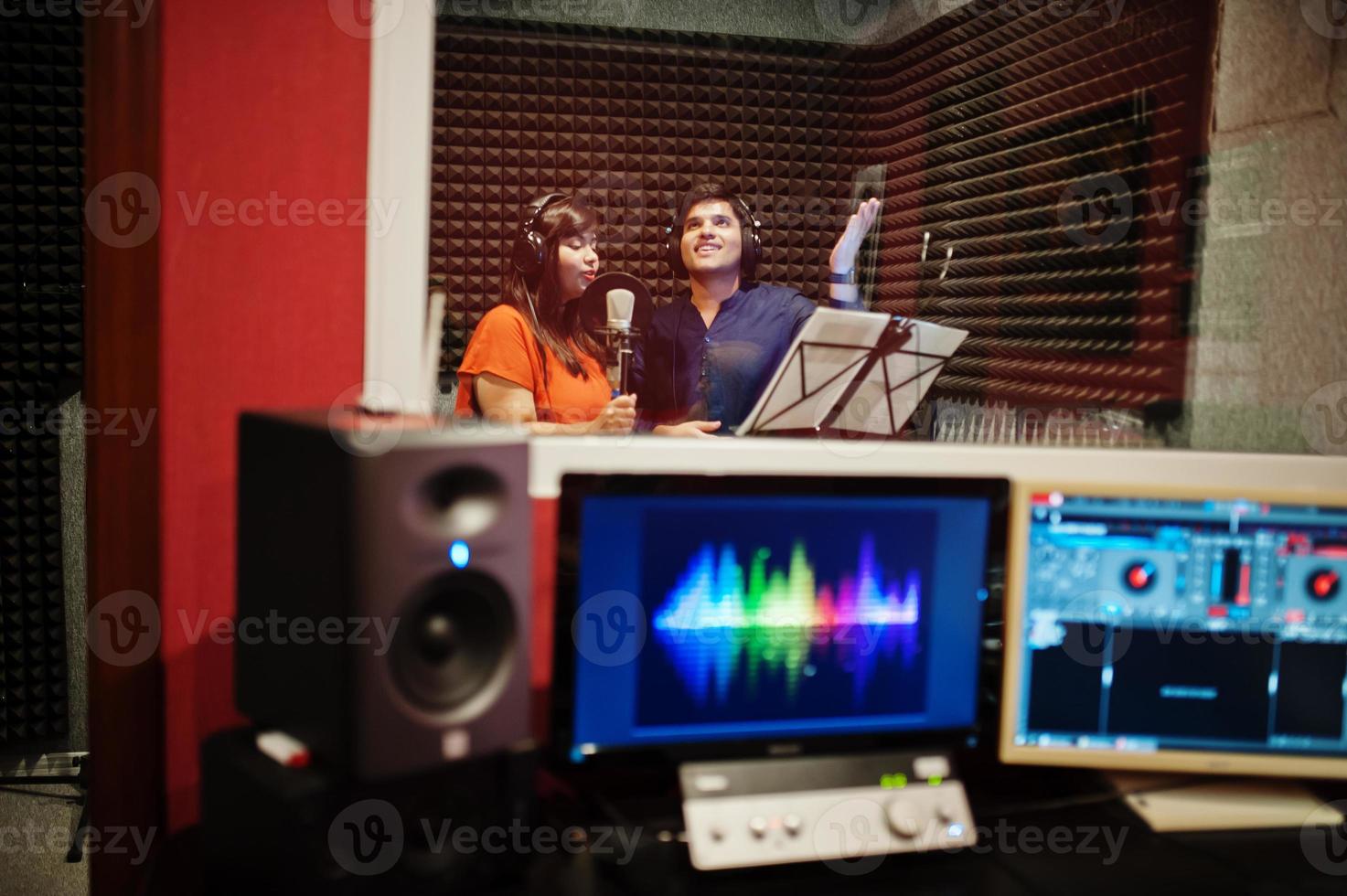 jóvenes cantantes de dúo asiáticos con micrófono grabando una canción en un estudio de grabación de música. foto