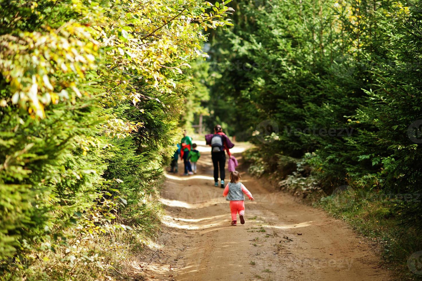 Mother with four kids resting in mountains. Family travel and hiking with childrens. Back of running baby girl. photo