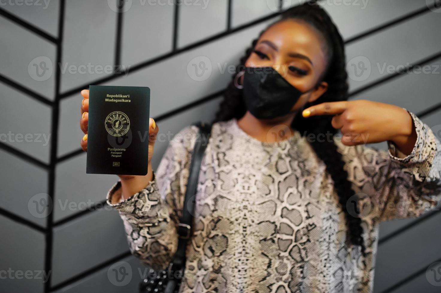 African woman wearing black face mask show Madagascar passport in hand. Coronavirus in Africa country, border closure and quarantine, virus outbreak concept. photo