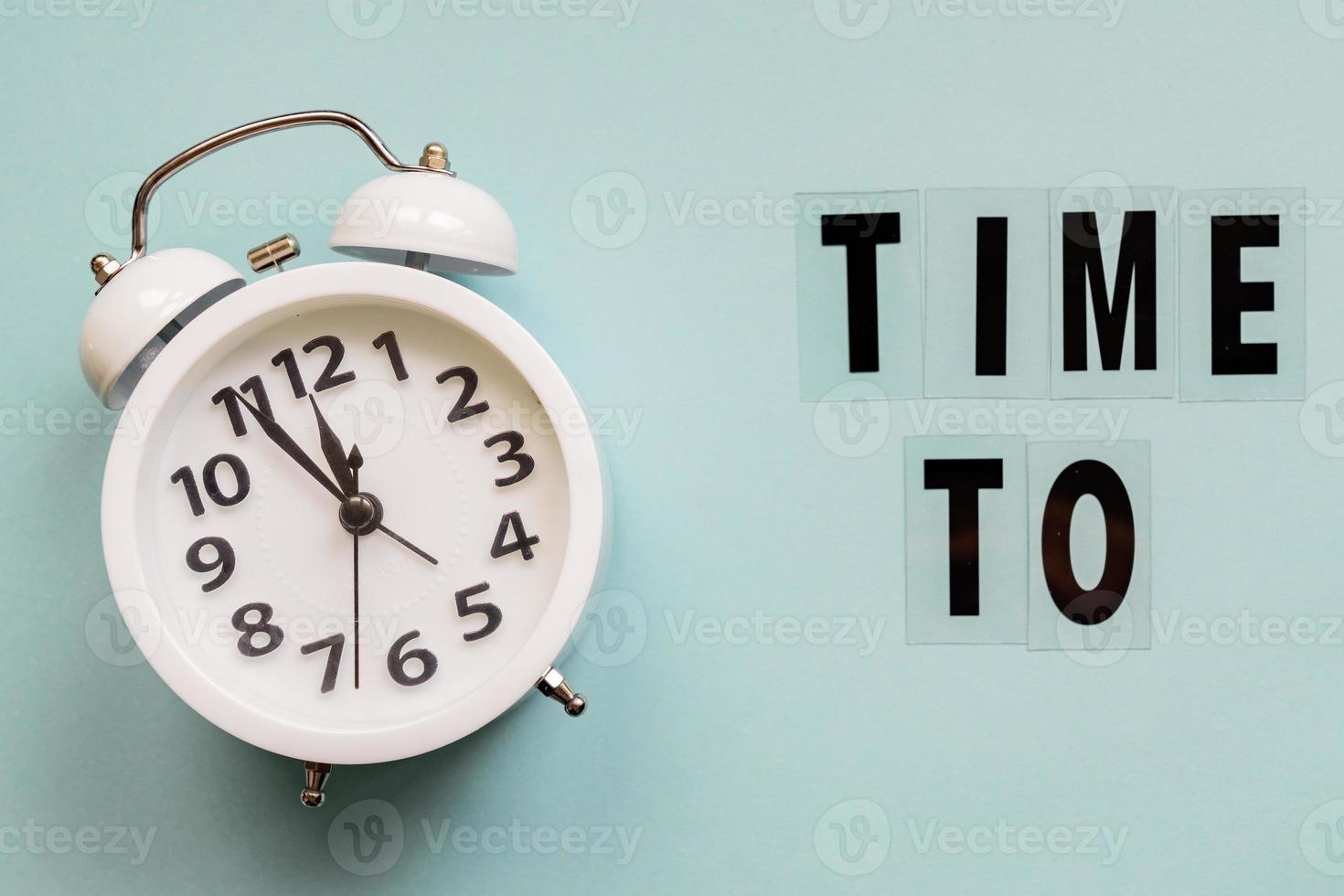 Business concept. time management. White alarm clock and text Time to on blue background. photo