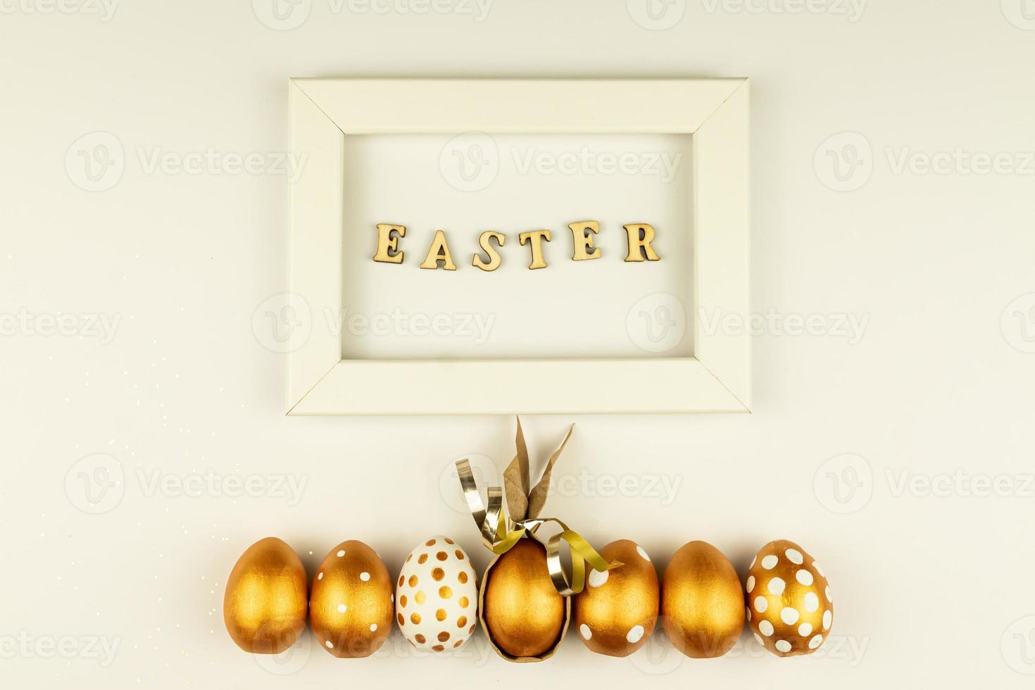 Easter festive decoration. Top view of easter eggs colored with golden paint and empty mock-up photo frame. Various dotted designs. White background.