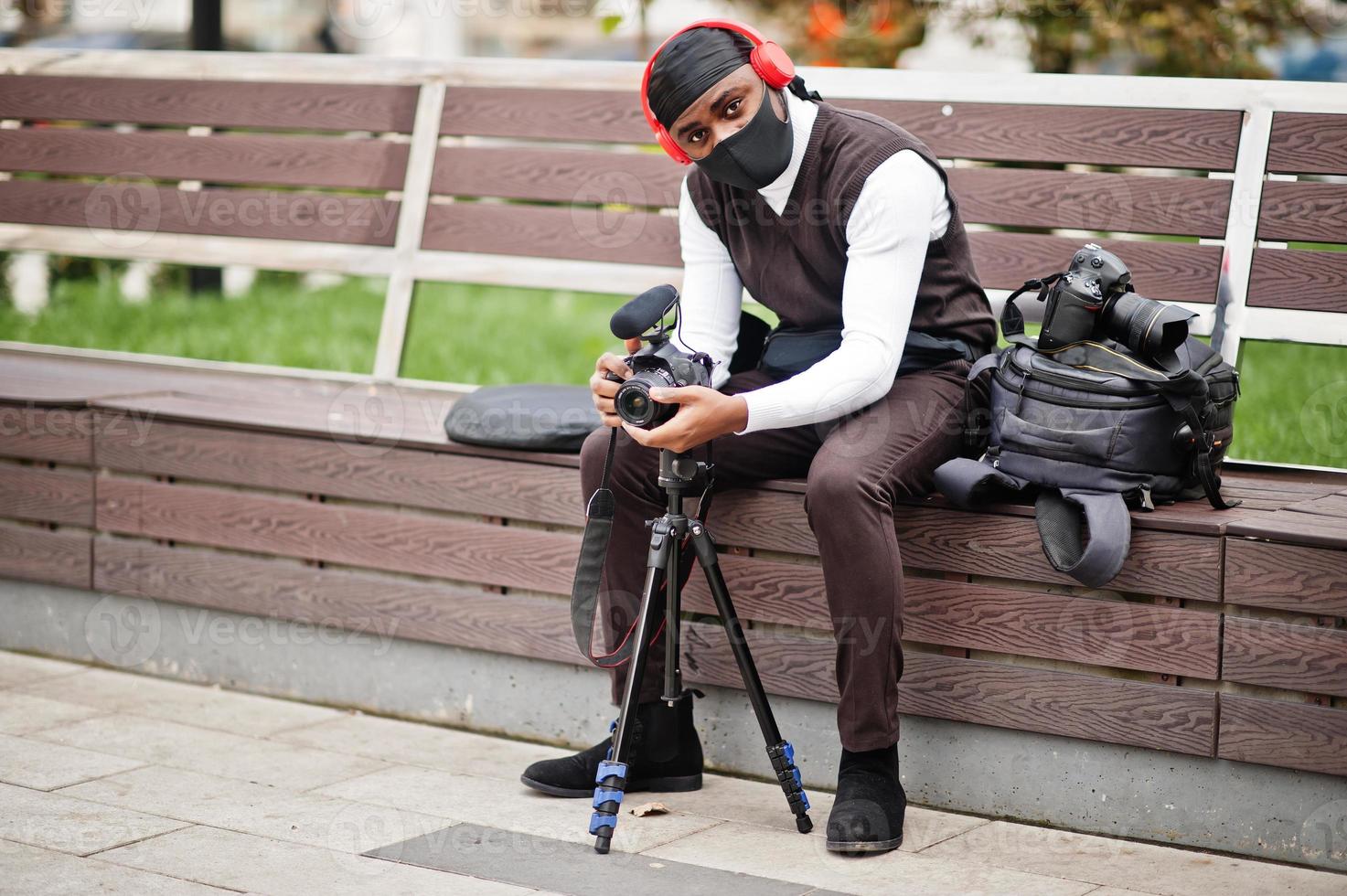 Young professional african american videographer holding professional camera with pro equipment. Afro cameraman wearing black duraq making a videos. photo