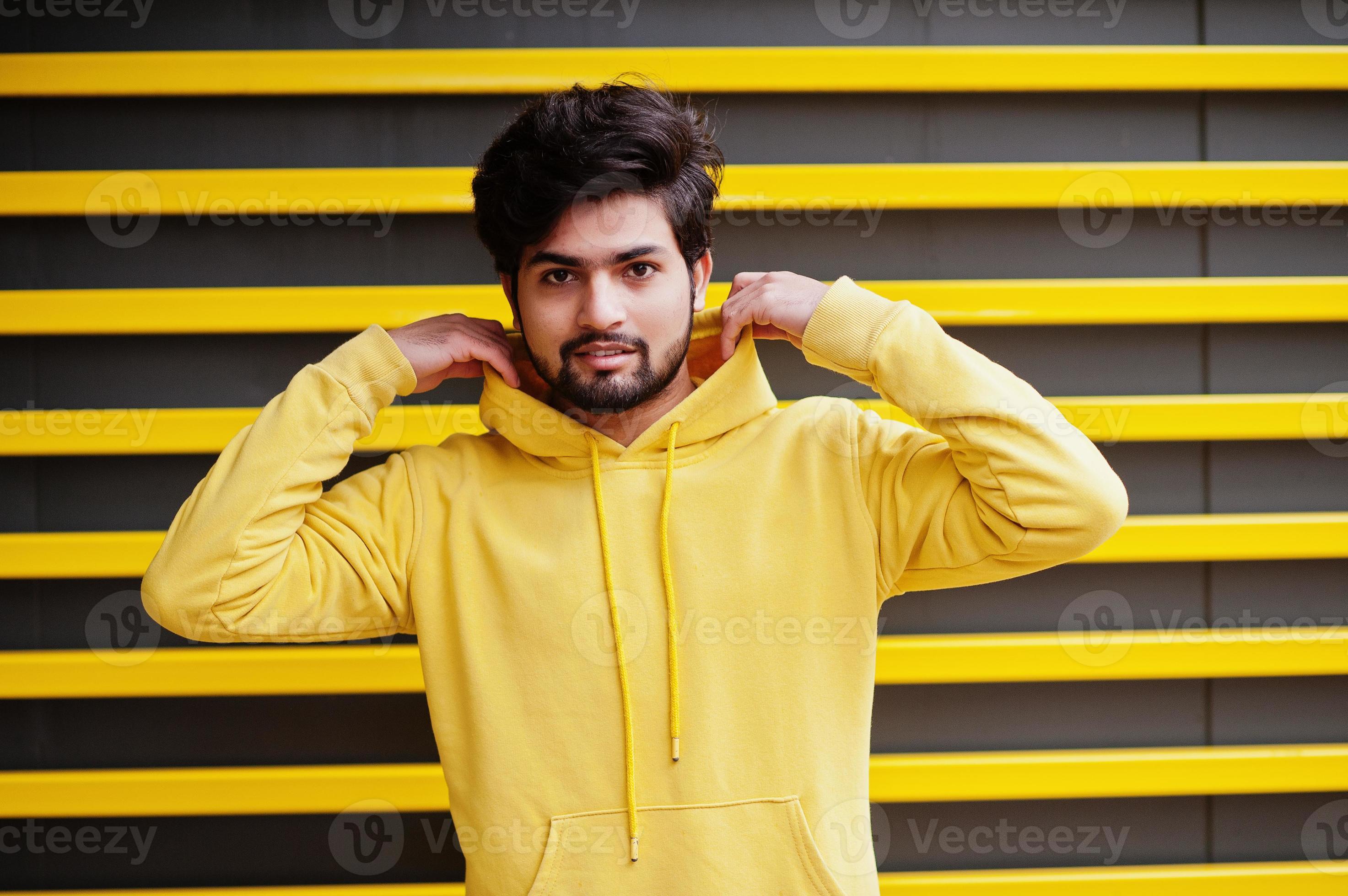 hombre indio joven hipster urbano en una sudadera amarilla de moda