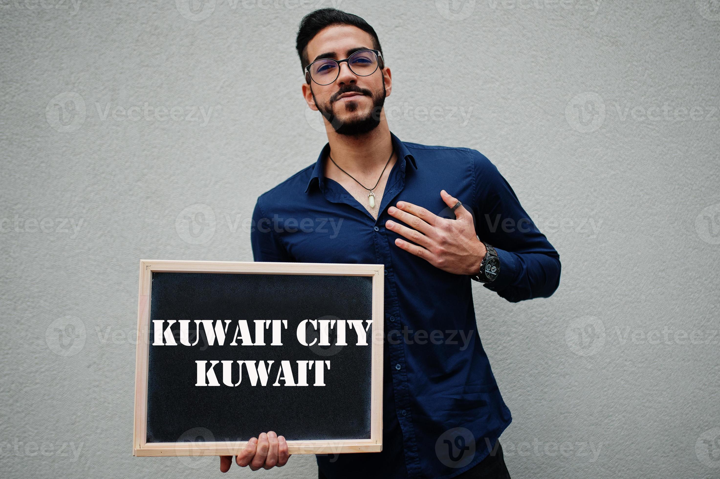 Arab man wear blue shirt and eyeglasses hold board with Kuwait City