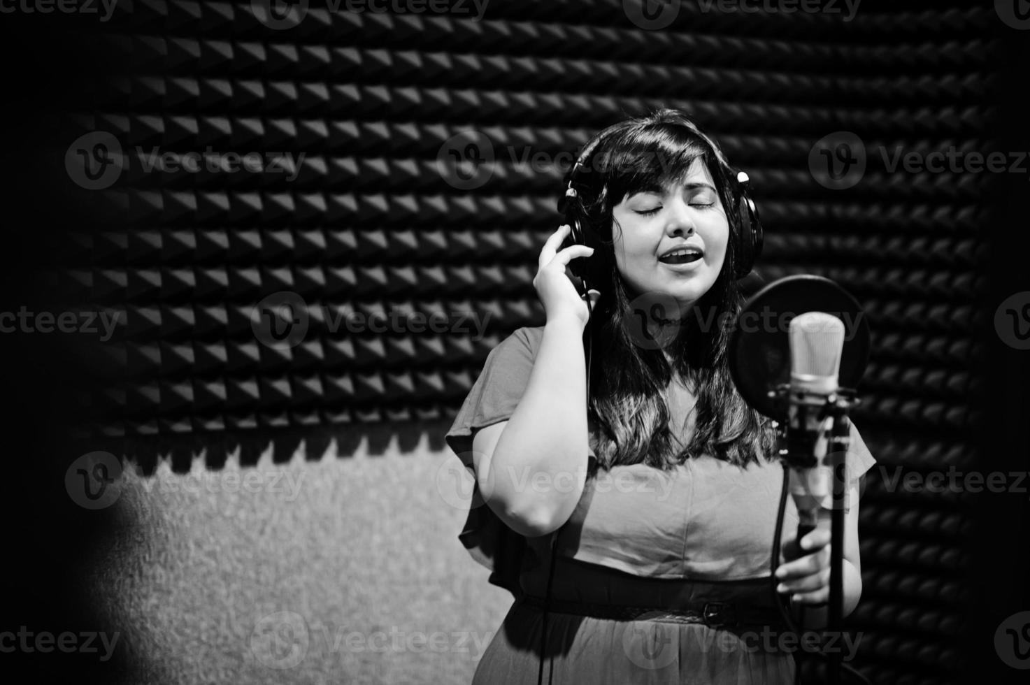 Young asian singer with microphone recording song in record music studio. photo