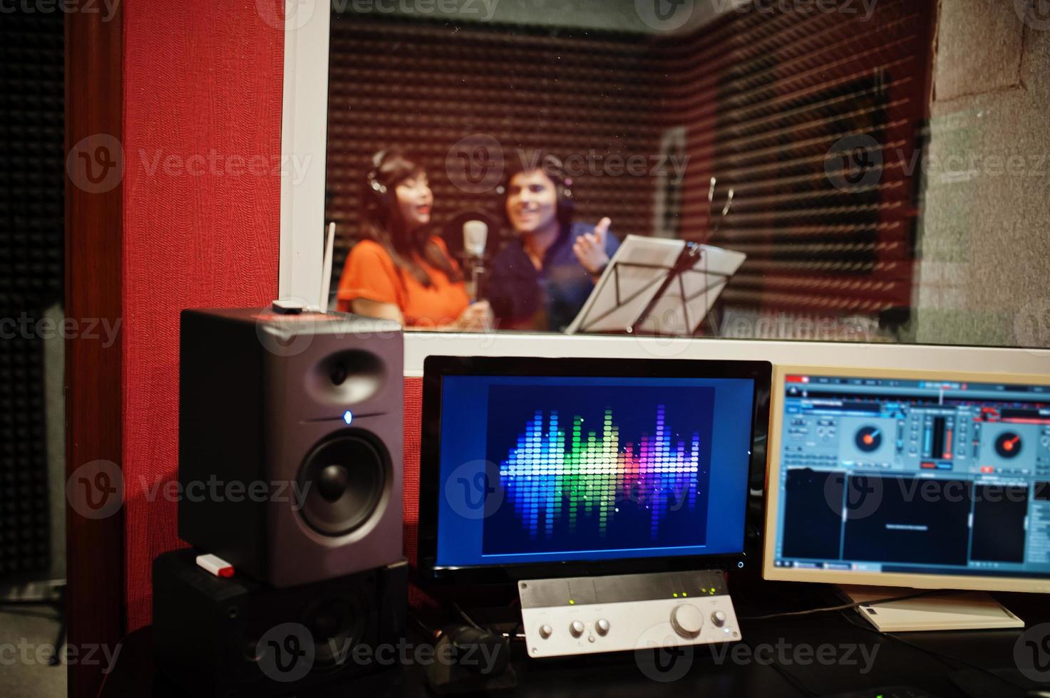 Young asian duet singers with microphone recording song in record music studio. photo