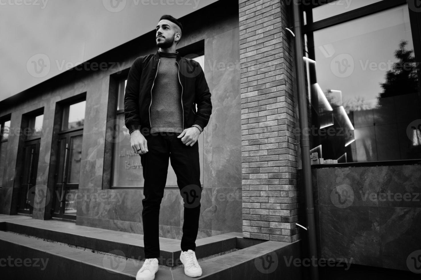 retrato de un elegante hombre de barba árabe con cuello alto gris y jaket negro. chico modelo árabe. foto