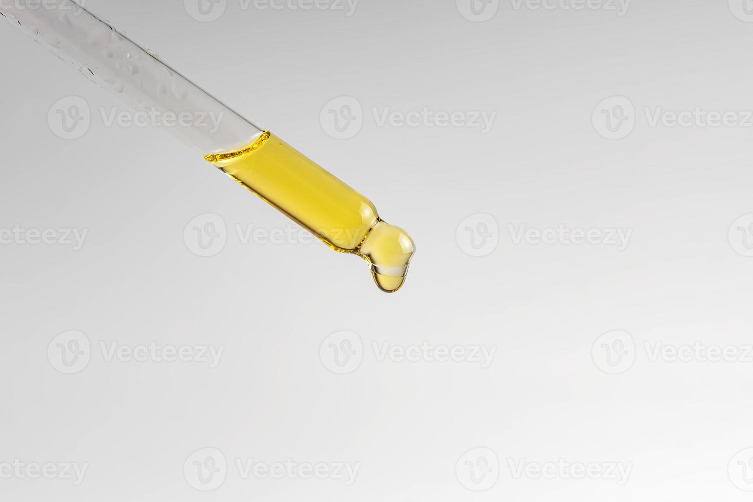 close up of pipette with pouring liquid serum on white background. Trendy cosmetics shot. Skin care concept photo
