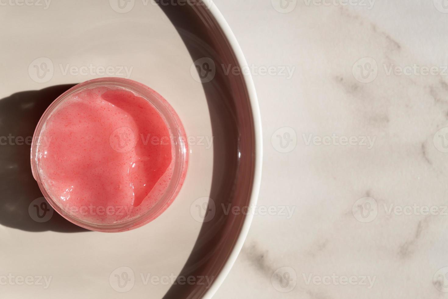 matorral de gelatina rosa con olor a fresas para el proceso de depilación sobre un fondo de mármol blanco foto