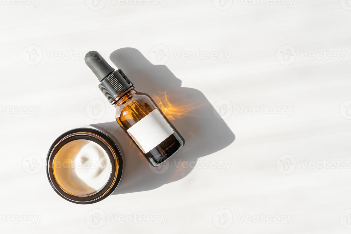 Face moisturizer cream, serum or beauty essential oil in dark glass bottles on whitee background. Flat lay, top view. Set for skin and body care beauty products. photo