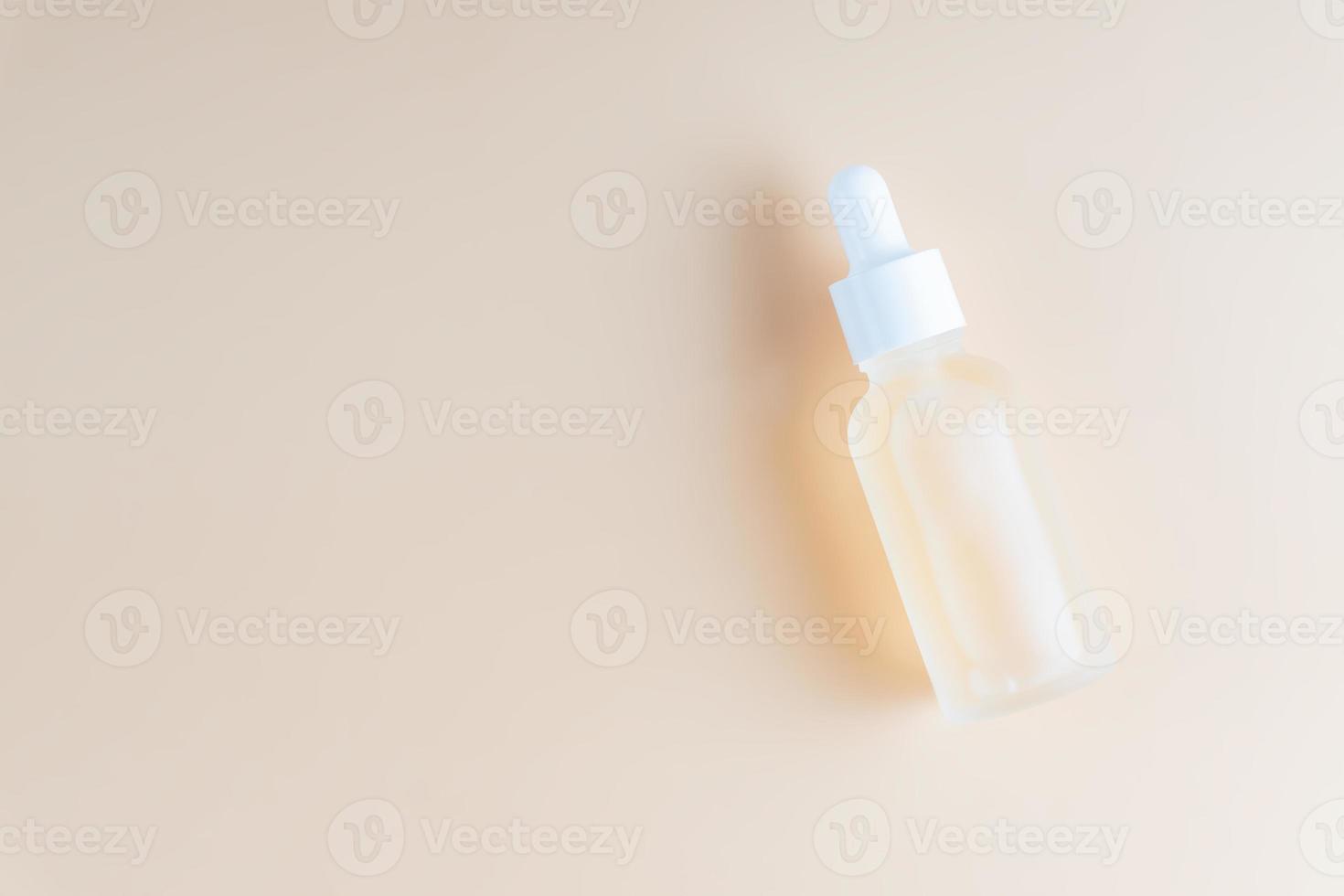 Skin care essence oil dropper glass bottle on beige background. Hydrating serum, vitamin for face skin. Aesthetic, minimalism. photo