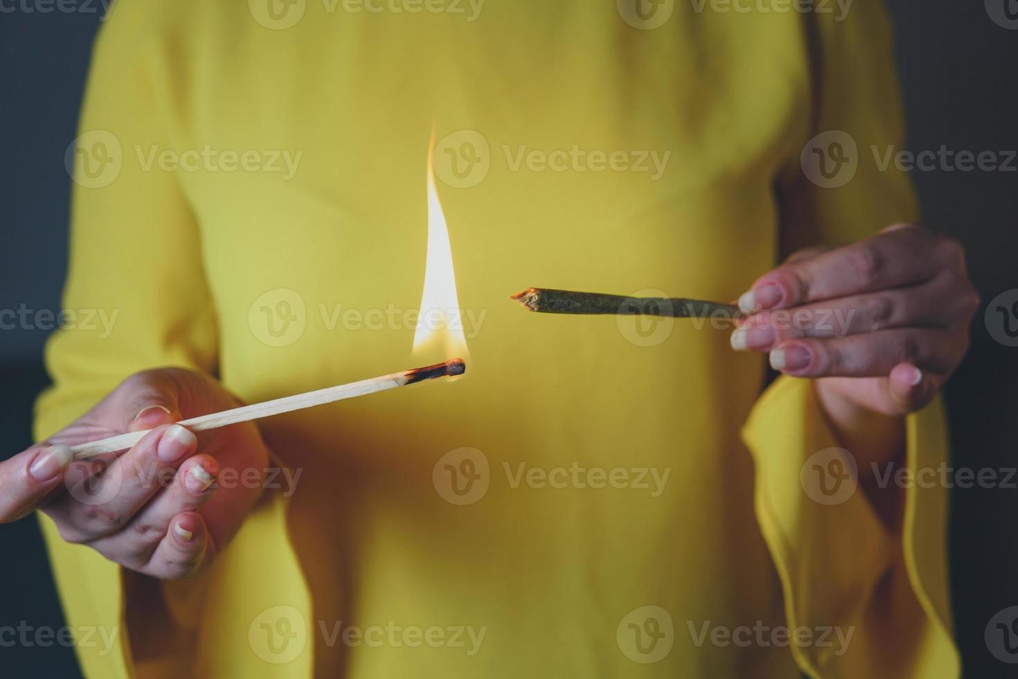 Close-up of adult woman lights up with matches and smoking medical marijuana joint. photo