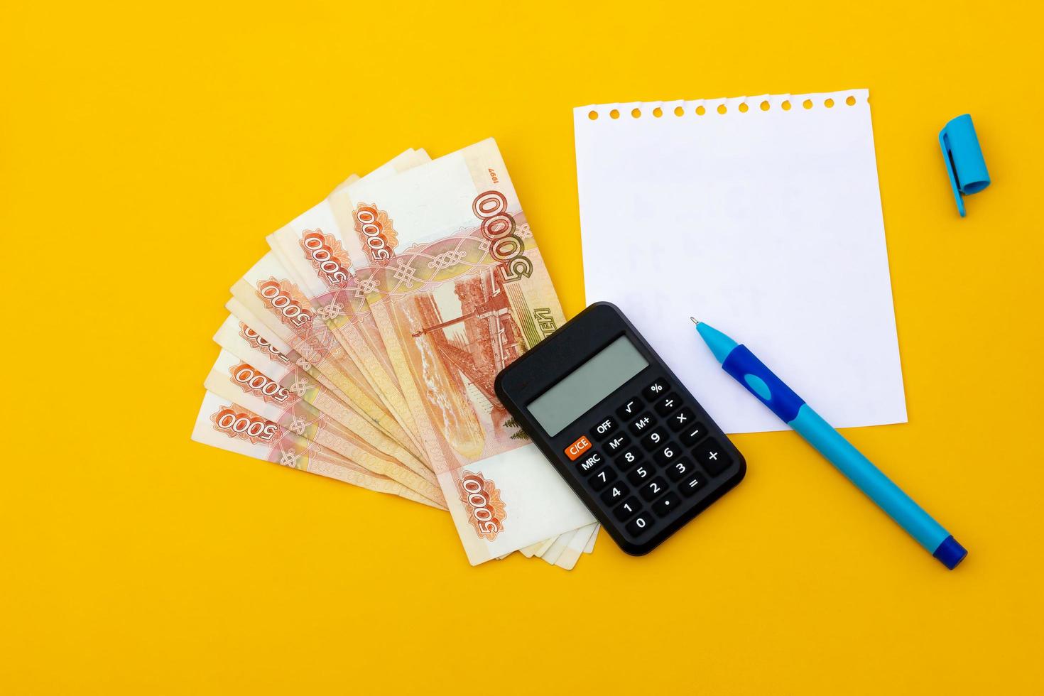 banknotes with a notepad and a pen on a yellow background. business concept photo