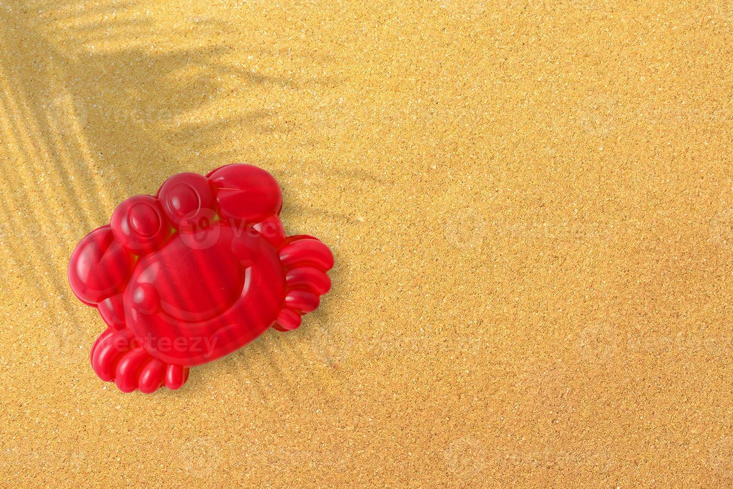 Red plastic shrimp on sand beach background, close-up. Childrens toys for bathing babies. Educational games for children, preschool education. Layout, preparation of toys for the designer or website. photo