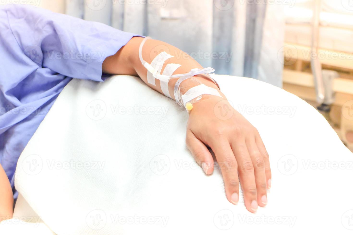 Close up of saline drip in patient's hand . Asian woman with  hospital admission. photo