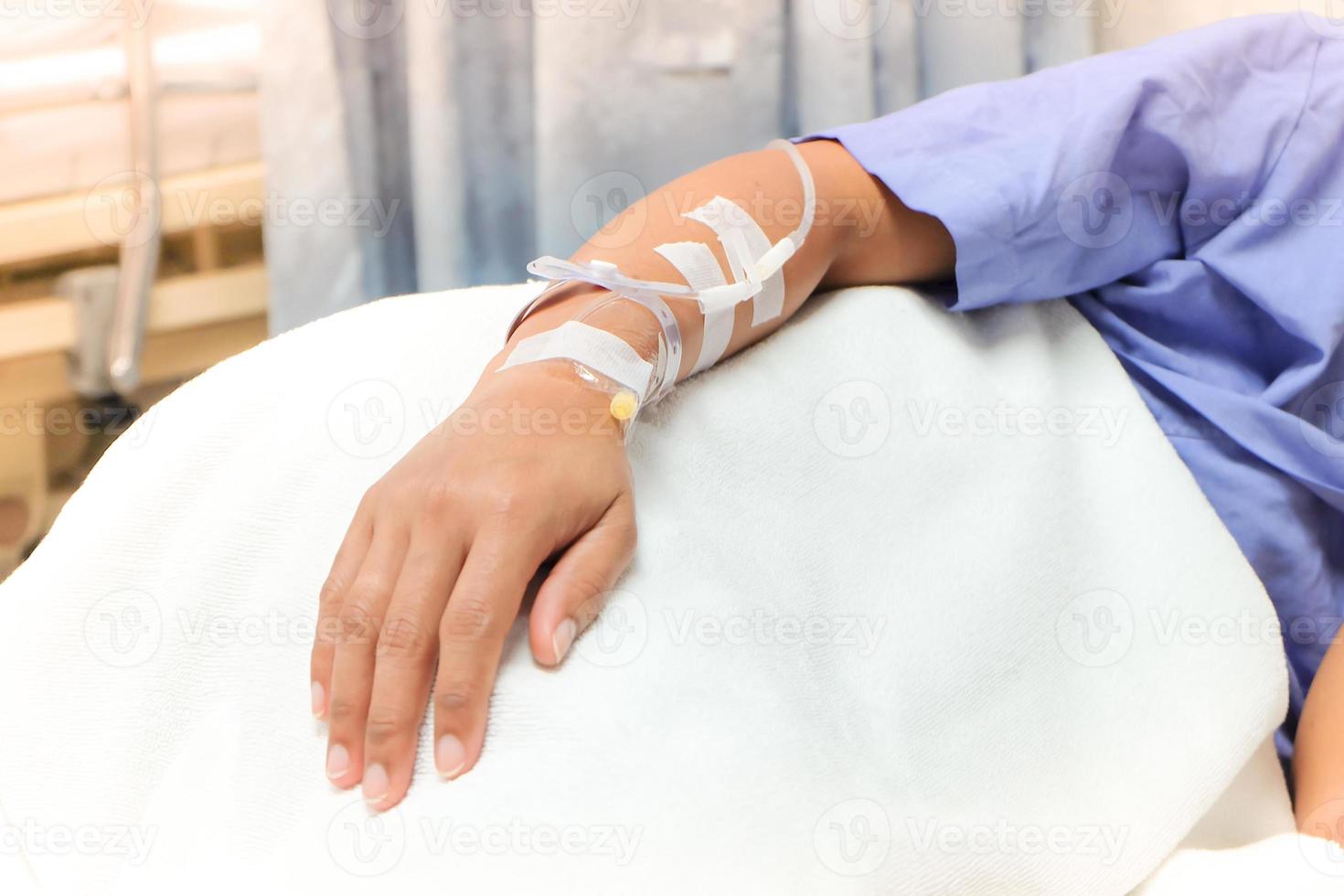 primer plano del goteo de solución salina en la mano del paciente. mujer asiática con ingreso hospitalario. foto