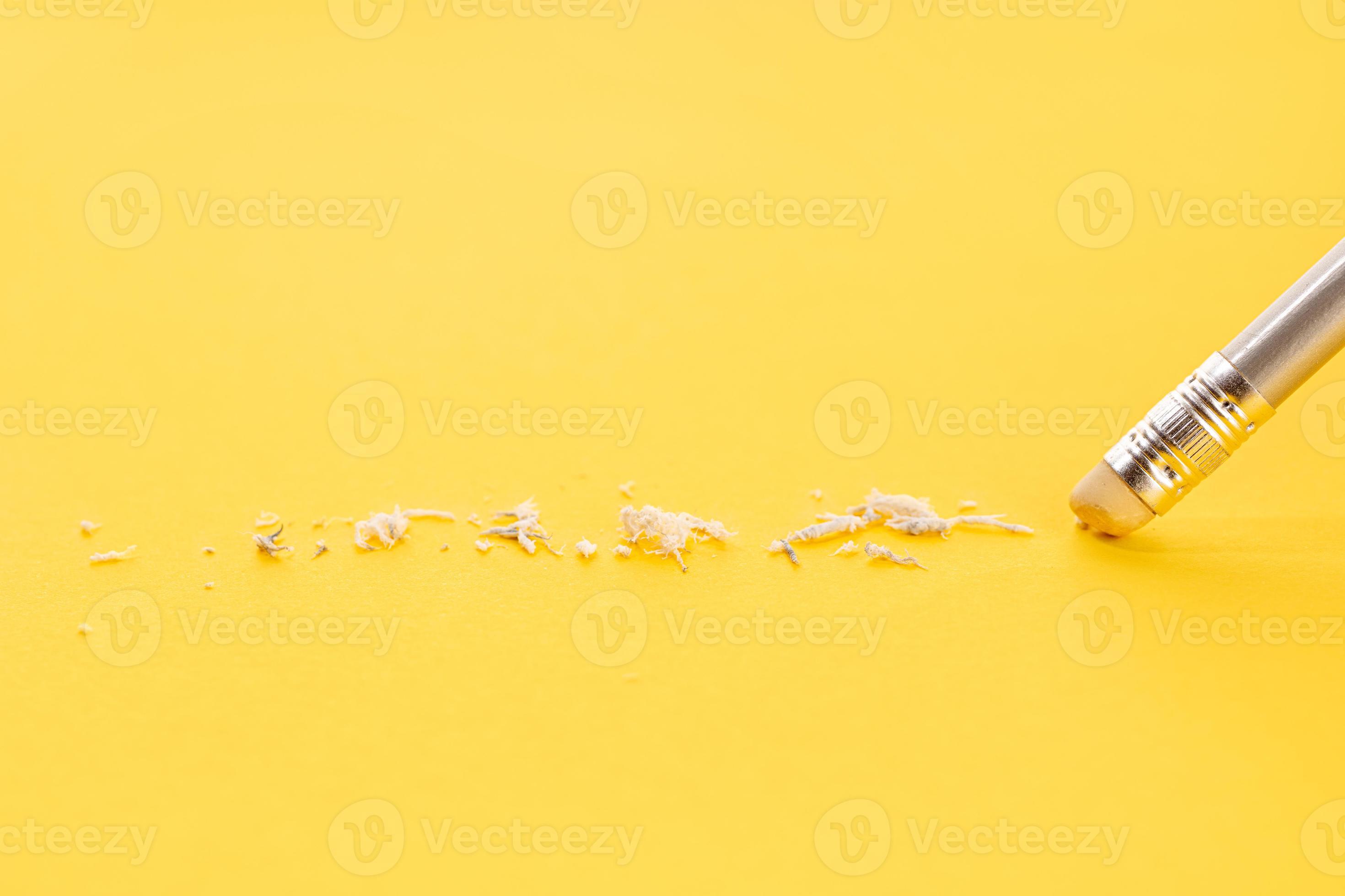 Pencil eraser working on yellow paper background. Mistake, erasing or