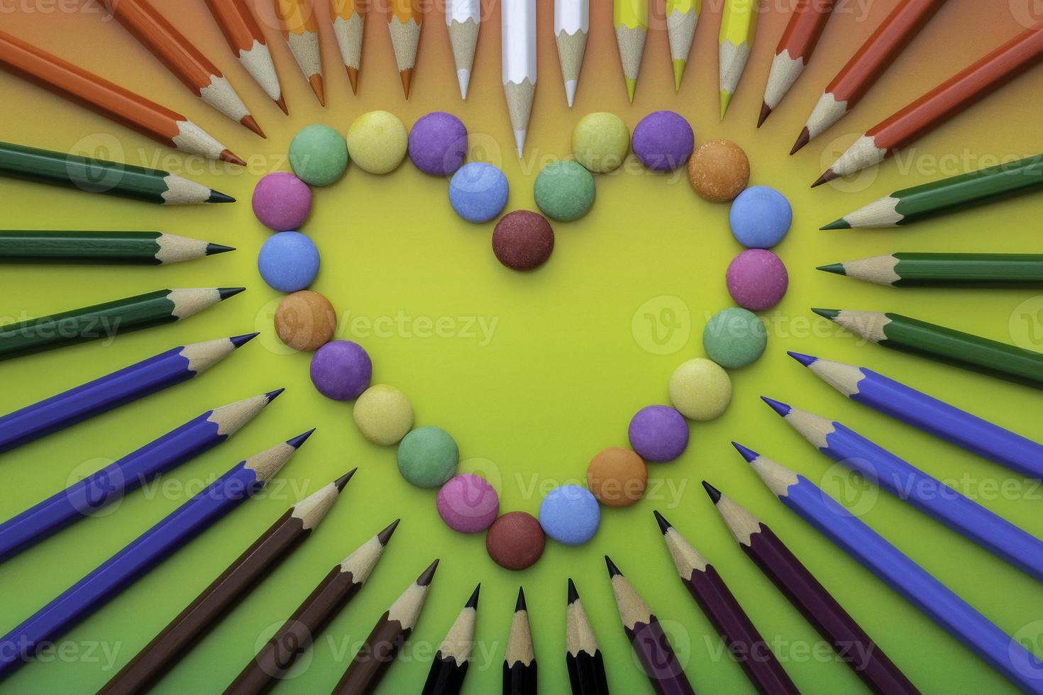 Multicolored heart shaped candies and  colored crayons photo