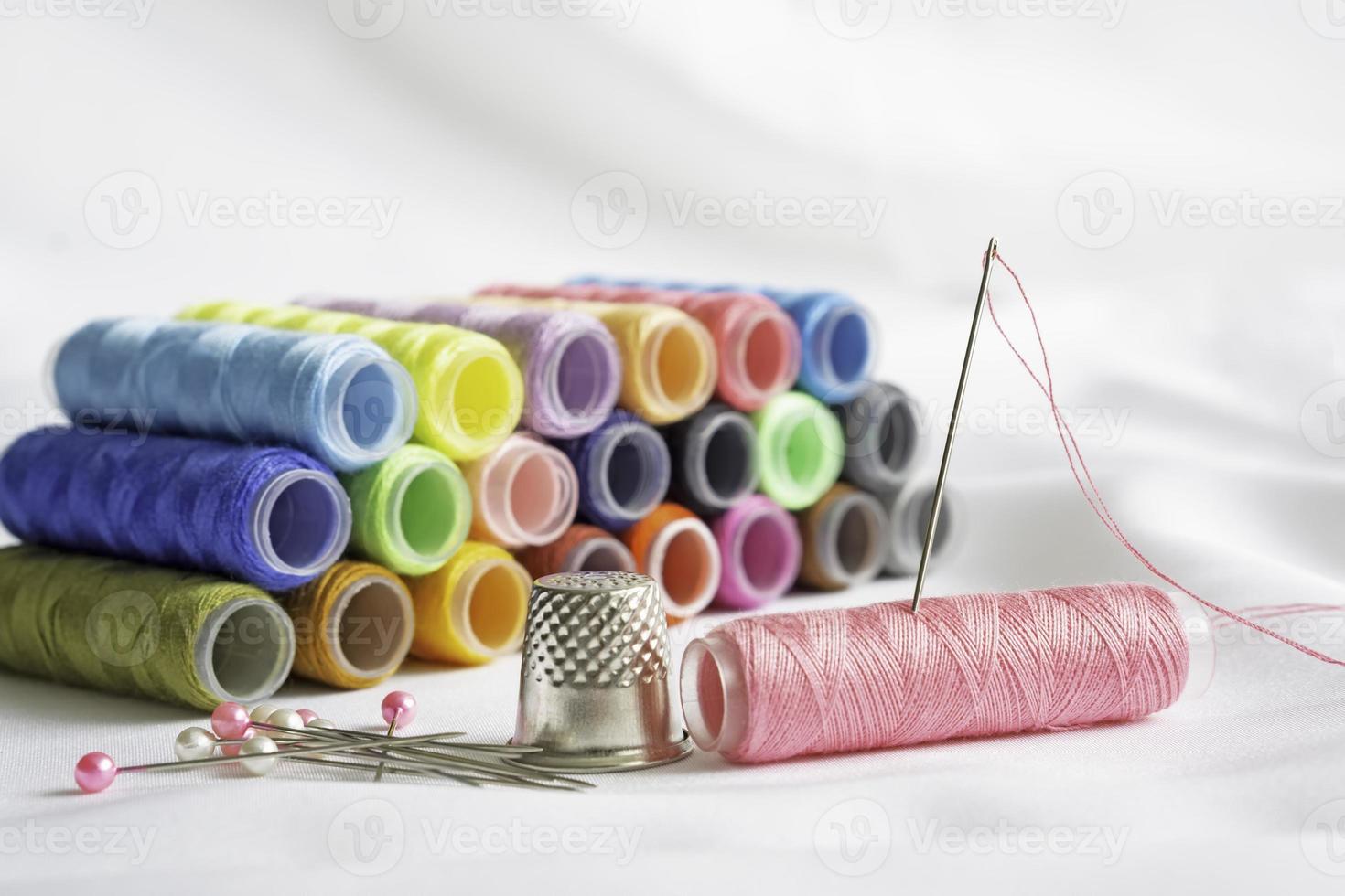 Needle, pins, thimble and colorful spools of thread photo