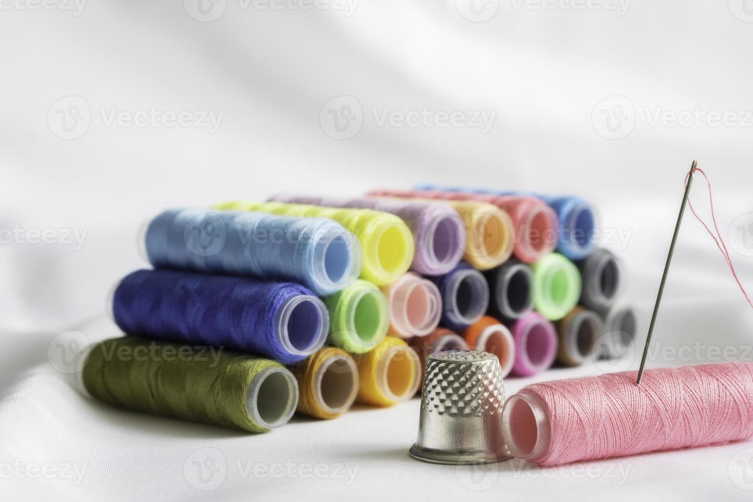 Needle,thimble and colorful spools of thread photo