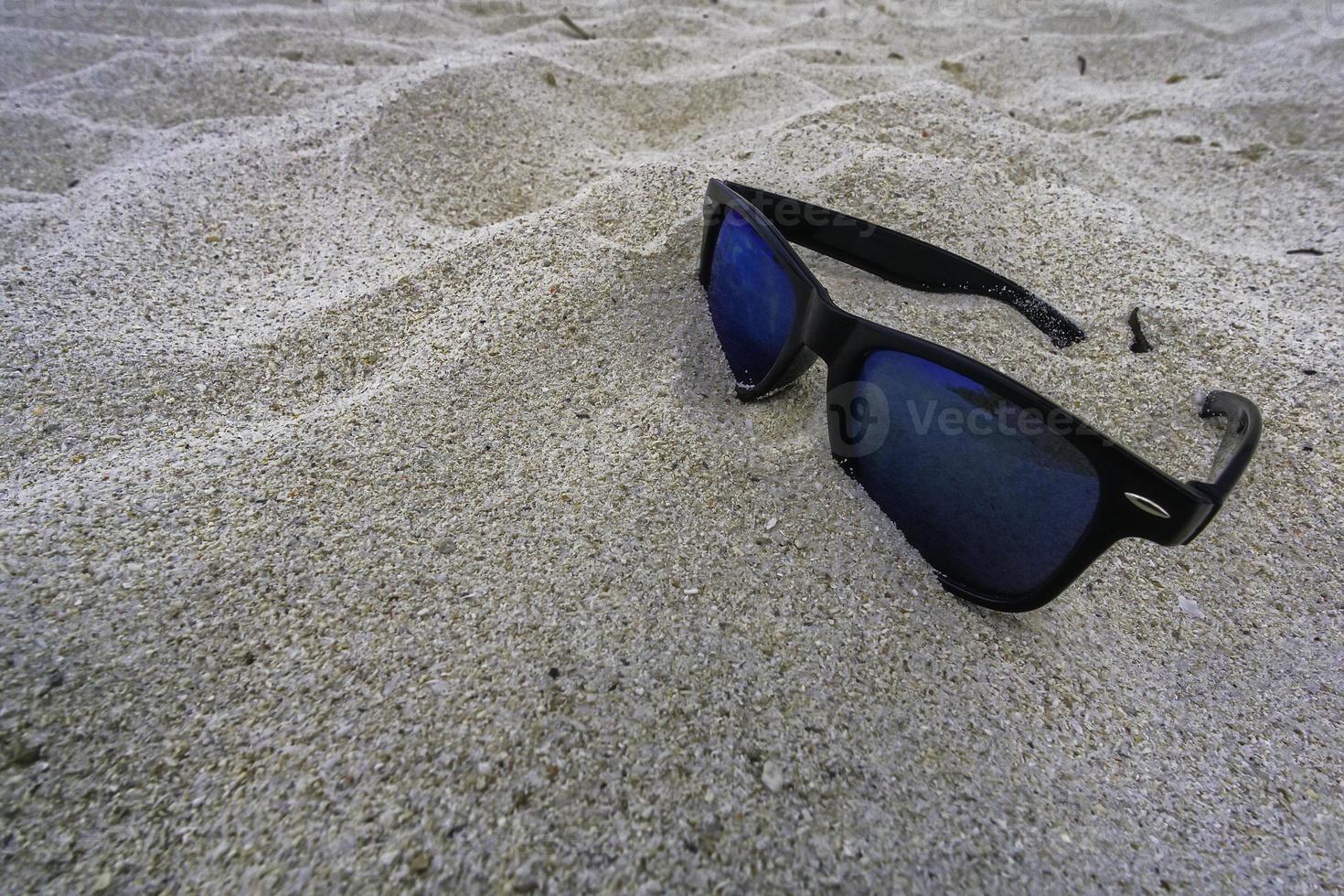 gafas de sol solitarias tiradas en una playa de arena foto