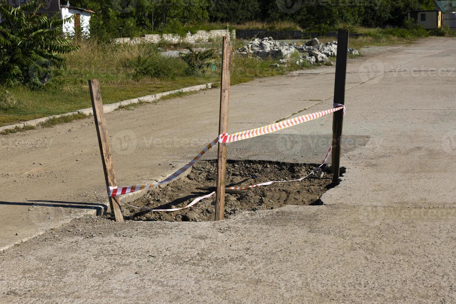 Bad automobile, pedestrian road with a large pit and a signal fence. photo