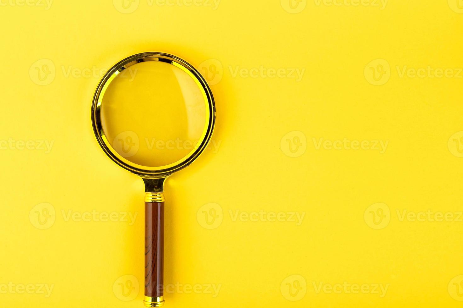 Magnifying glass in a gold frame on a yellow background. Copy space. photo