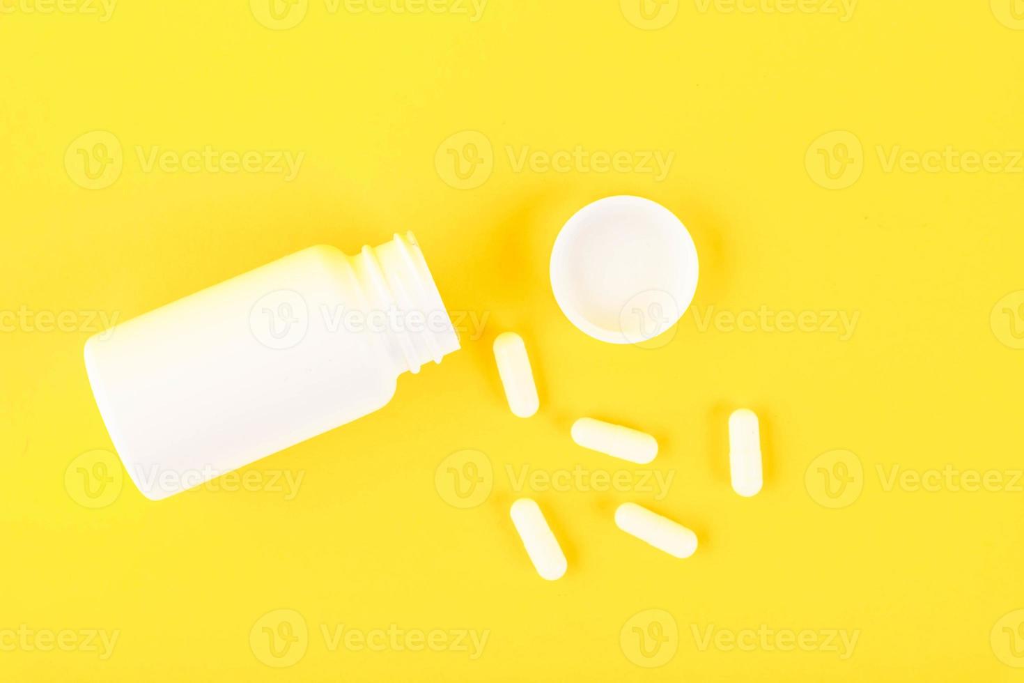 plástico blanco, botella médica con pastillas, cápsulas sobre un fondo amarillo. copie el espacio foto