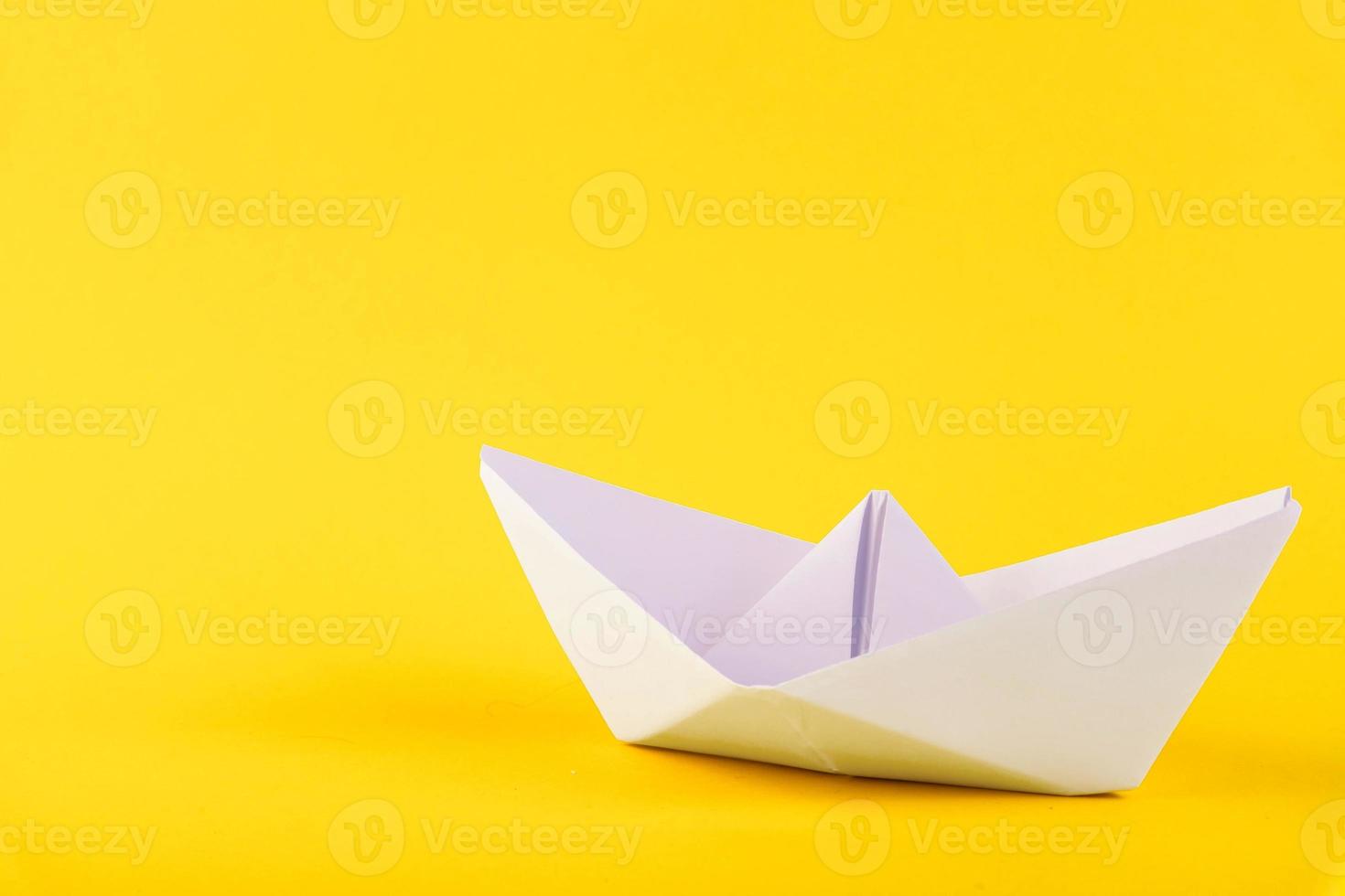 White paper boat on a yellow background. Copy space. photo