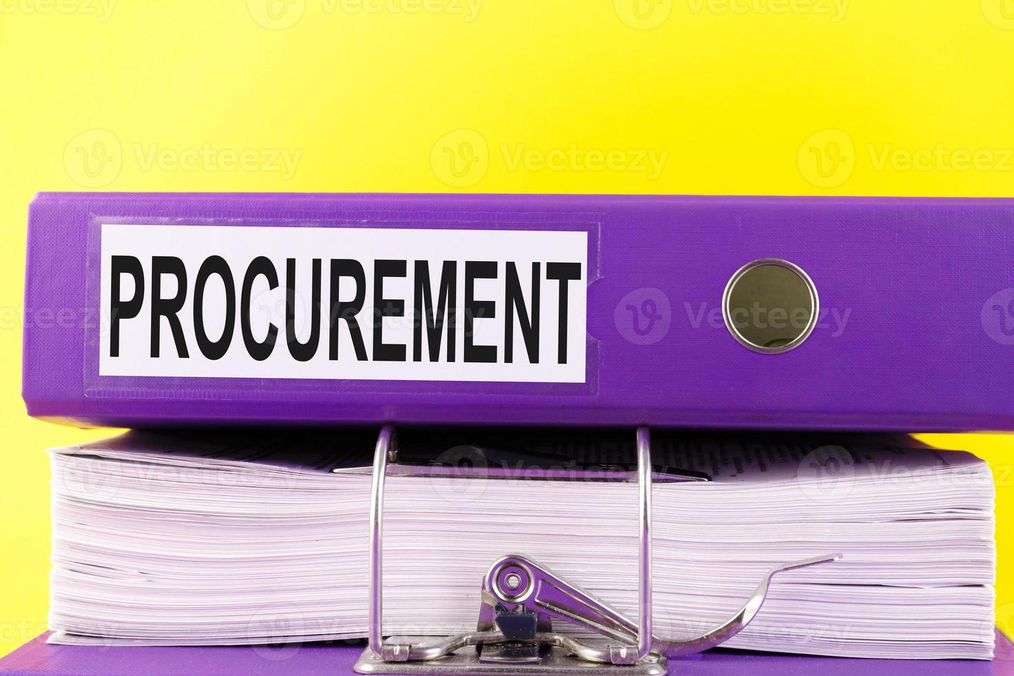 The Procurement text is written on an office folder on a pile of papers with a yellow background. Copy space. photo