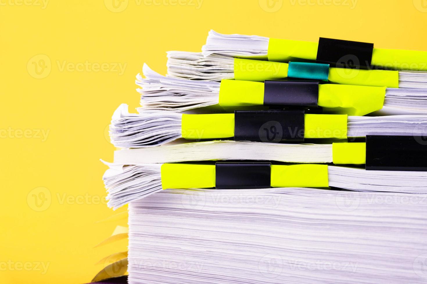 Piles of white papers work large piles of papers stacked together. On the desk in the office with black clip. Documents that are not finished. Business concept. photo