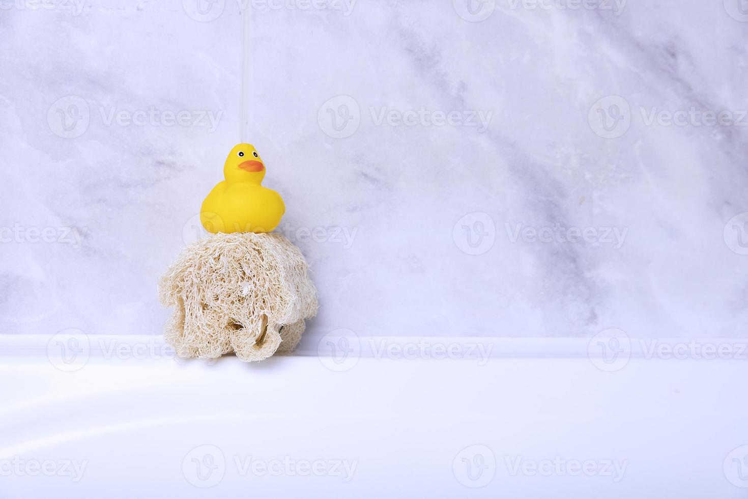 Children's hygiene products concept. Yellow duckling in the bathroom on a background of gray tiles. Copy space photo