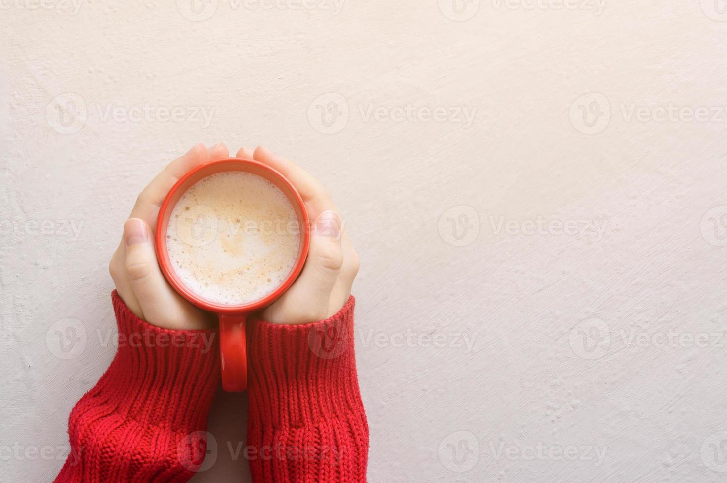 Top view hands holding red cappuccino mug. The atmosphere of sunny autumn. Background with copy space. photo