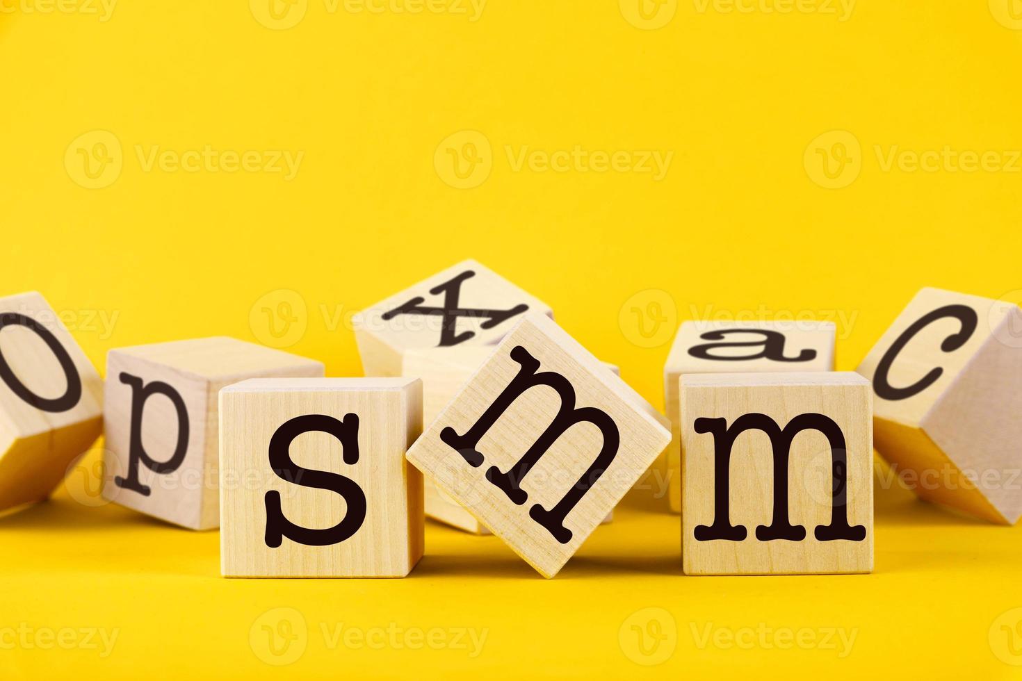 The conceptual word SMM is written on wooden cubes and a yellow background. photo
