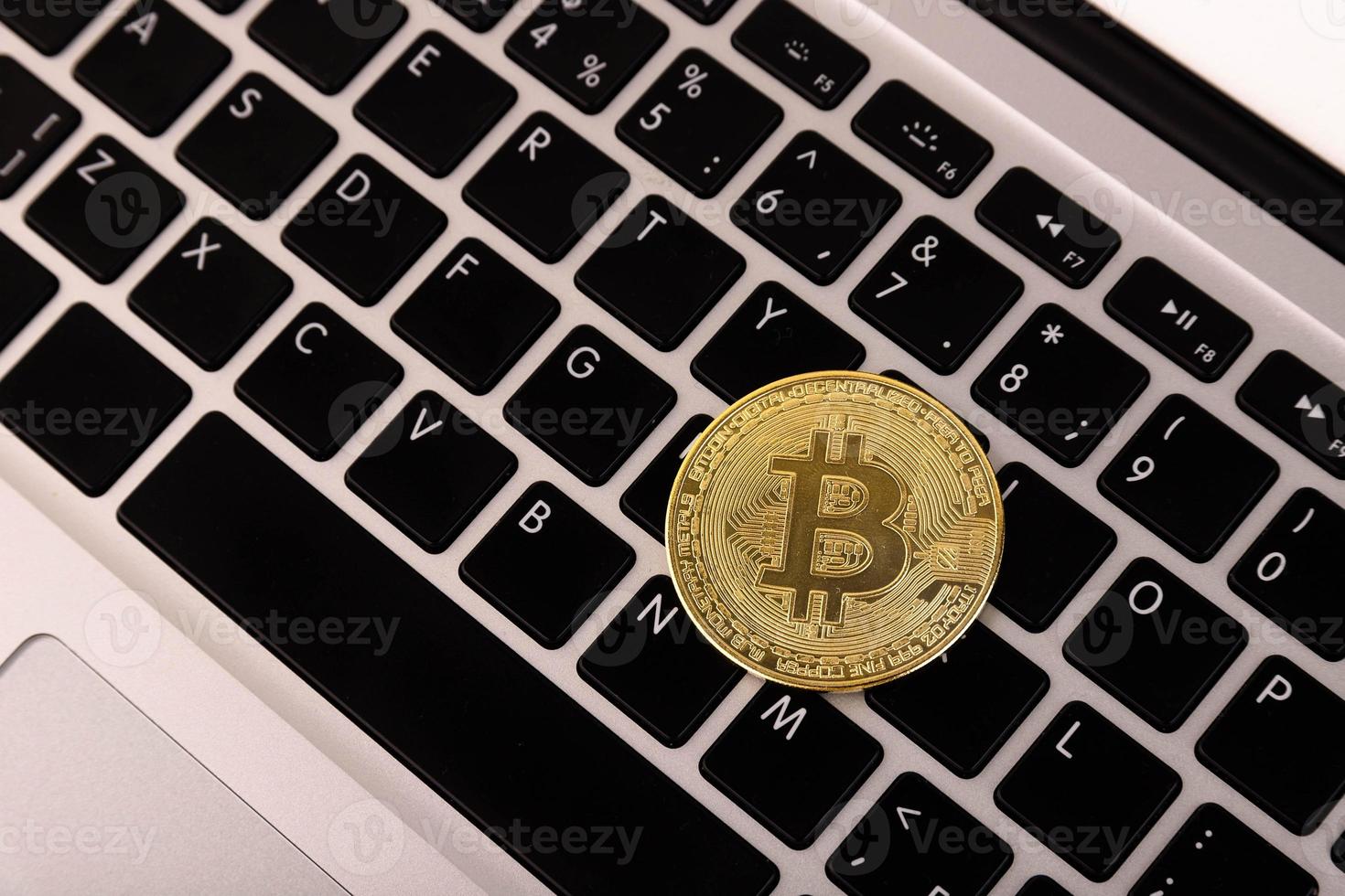 Gold coin Bitcoin, lies on a laptop, keyboard. with a flat layout. photo