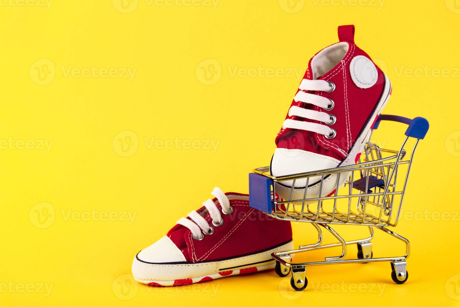 A pair of red sneakers in a trolley on a yellow background. Online shopping. electronic commerce. Copy space. photo